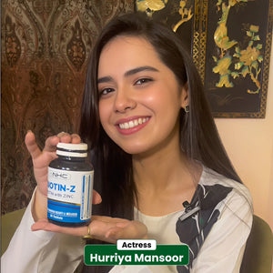 Actress Hurriya Mansoor smiling and holding NHC Biotin-Z Biotin with Zinc supplement for beauty and wellness