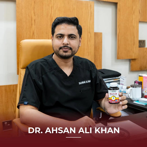 Dr. Ahsan Ali Khan holding NHC Multi-W One-A-Day Women multivitamin supplement bottle at his clinic desk
