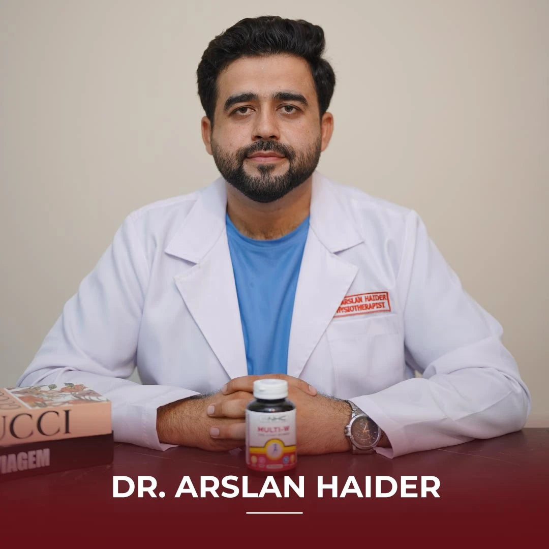 Dr. Arslan Haider, physiotherapist, sitting at a desk with NHC Multi-W One-A-Day Women multivitamin supplement bottle