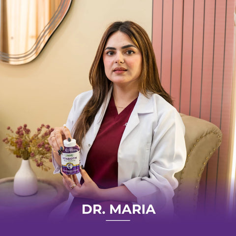  Dr. Maria in white lab coat holding NHC VitaBiotin 5000mcg biotin supplement bottle at her clinic